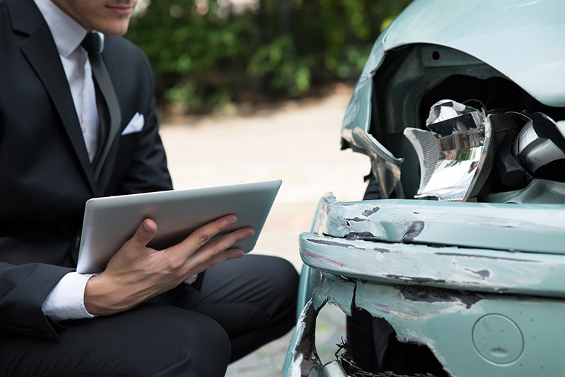 Image of man with a tablet and a damaged car